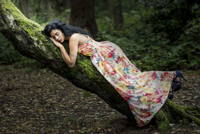 Side view of young woman sleeping on tree at forest