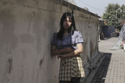 Full length of woman standing against wall