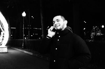 Man holding smart phone while standing on street at night