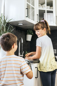 Children wash and dry dishes in the kitchen. little helpers