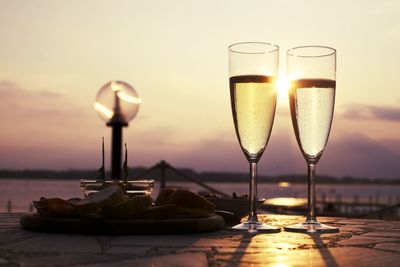 Champagne flutes against sky during sunset