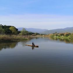 Man on boat in lake against sky