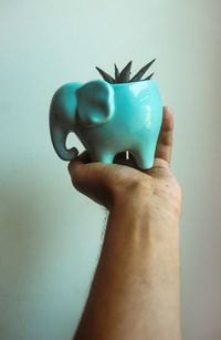 Close-up of human hand against colored background