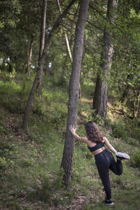 Woman standing by tree trunks in forest