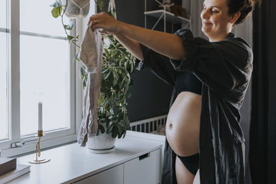 Pregnant woman organizing baby clothes and getting ready for baby arrival