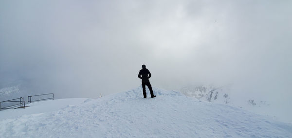 Rear view of person on snowcapped mountain against sky