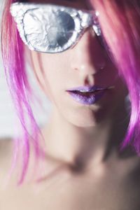 Close-up portrait of topless young woman with purple hair wearing sunglasses