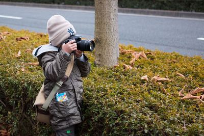 Girl photographing by hedge