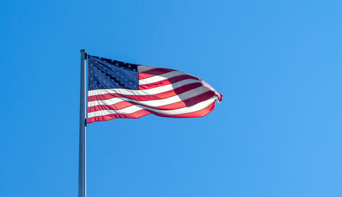 Low angle view of flag against clear blue sky