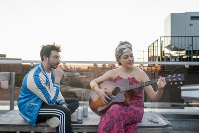 Young woman playing guitar for her friend