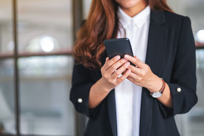 Midsection of businesswoman using phone in office