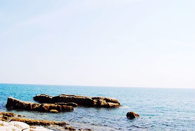 Scenic view of rocks in sea against clear sky