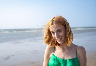 Portrait of young woman standing at beach