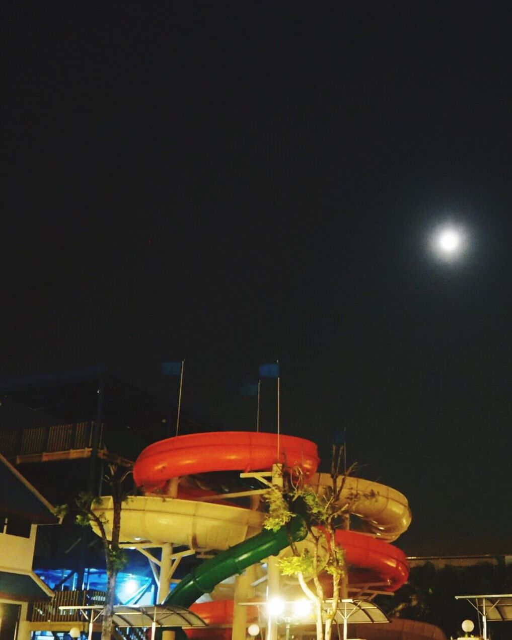 LOW ANGLE VIEW OF ILLUMINATED CAROUSEL AGAINST CLEAR SKY AT NIGHT