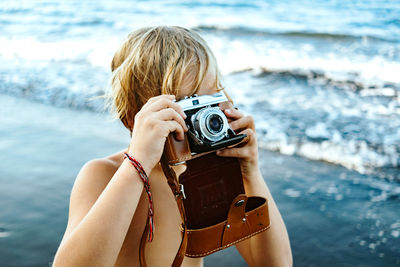 Midsection of woman photographing against sea