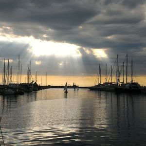 Boats moored on lake against cloudy sky during sunset