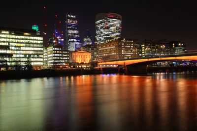 Thames river by illuminated buildings in city