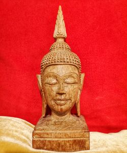 Close-up of buddha statue against red wall