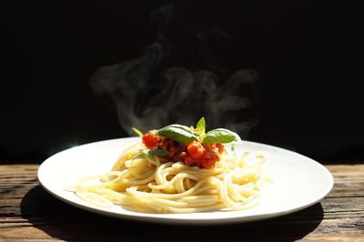 Delicious italian pasta spaghetti bolognese and tomato sauce with hot steaming on wood table 