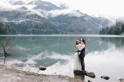 A happy couple in love and married embrace in nature by the lake and the misty mountains