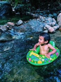High angle view of shirtless boy with inflatable ring pond