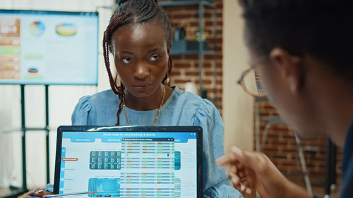 Portrait of young woman using laptop at office