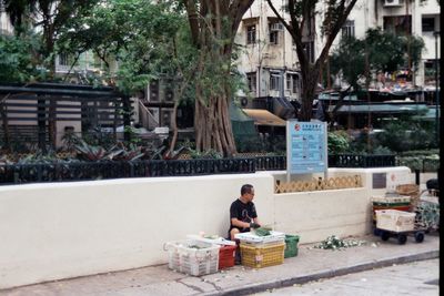Man sitting by building in city