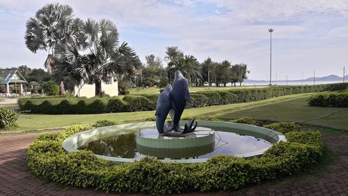 Statue by palm trees in park against sky