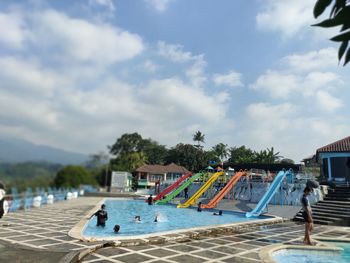 People by swimming pool against sky