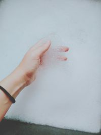 Cropped image of hand holding wet leaf