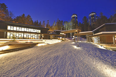 Snow covered land and buildings against blue sky