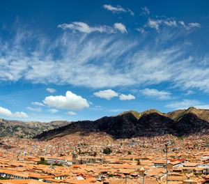 Scenic view of town by mountains against sky