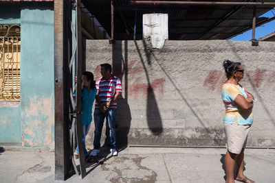 People standing on footpath against wall