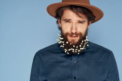 Portrait of young man wearing hat against blue background