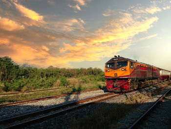 Train on railroad tracks against sky during sunset