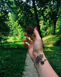 Midsection of person holding fruit against trees