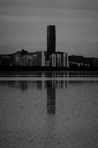 Reflection of buildings in lake against sky in city