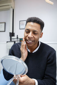 Close-up of man looking at mirror in clinic