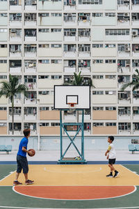 Full length of man playing basketball on building