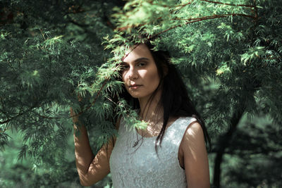 Portrait of young woman standing amidst tree branches