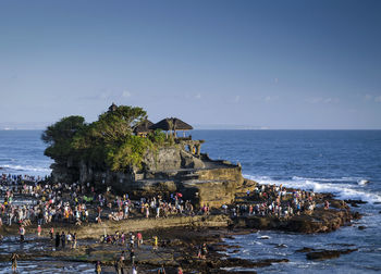 People on beach by sea against sky