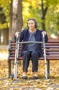 Senior woman with walker sitting on bench at park