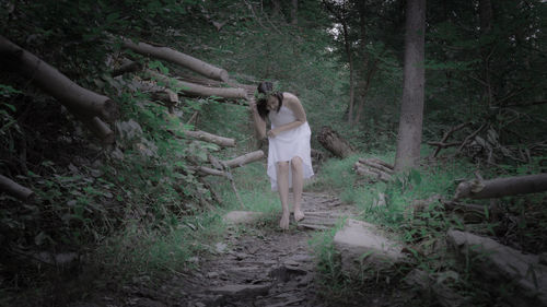 Woman standing by tree in forest