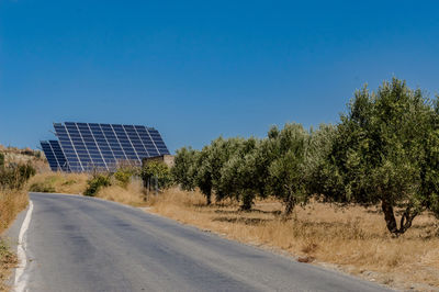Four photovoltaic panels on a hill above a olive tree field on the island of ccrete in greece