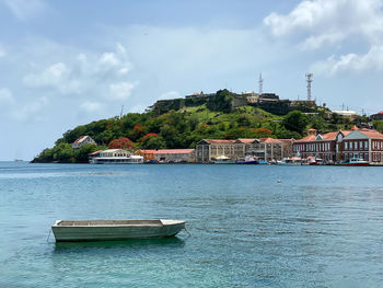 Sailboats in sea by buildings against sky