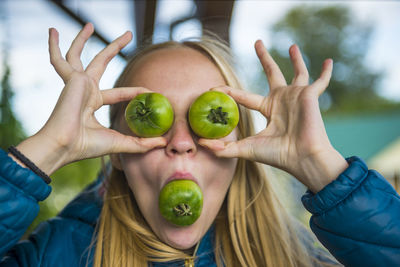 Young woman playing with green tomato