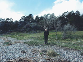 Senior man standing on field against sky