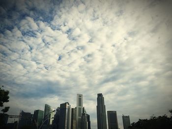 Low angle view of modern buildings against cloudy sky