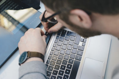 High angle view of computer programmer fixing digital tablet to keyboard at desk in office