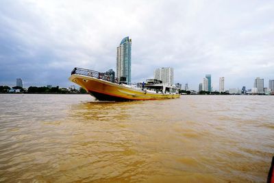 Ship in river against sky in city